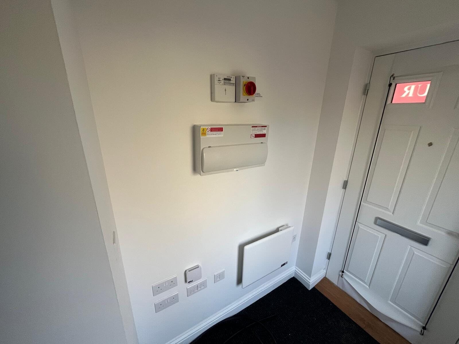 Hallway with a fire alarm panel, call point and panel heater