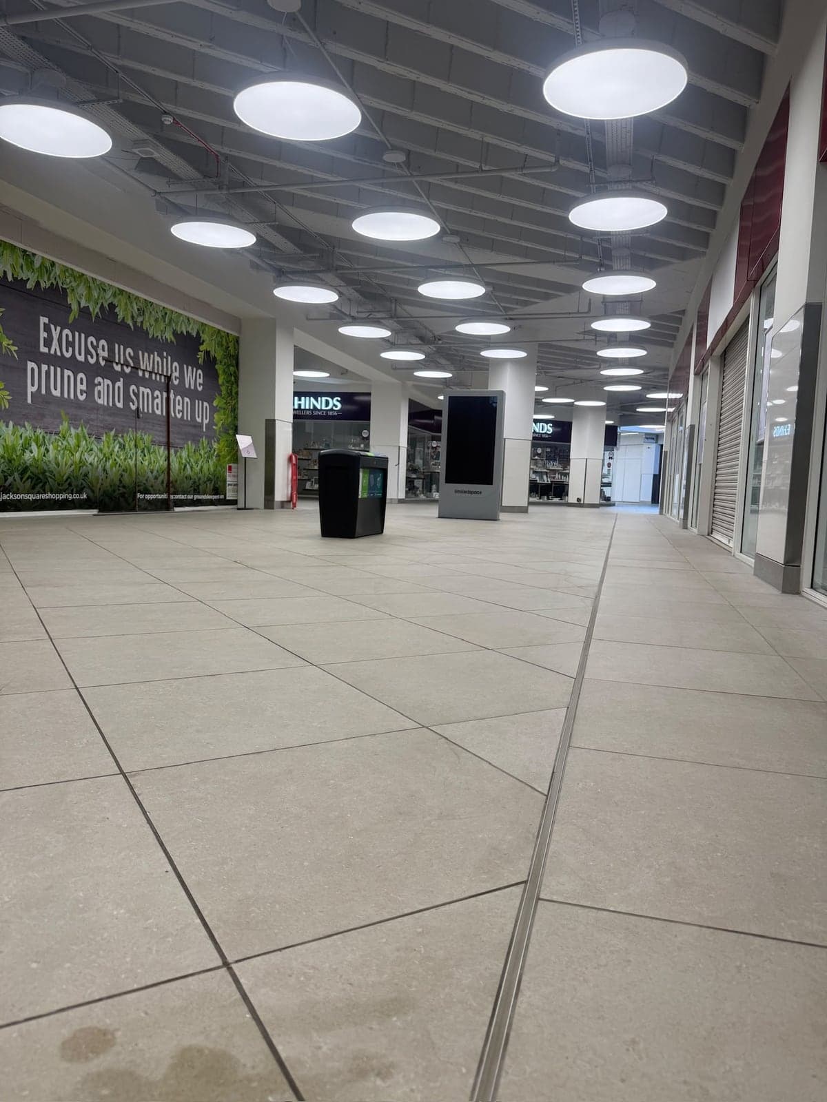 Rows of large round ceiling lights along a shopping centre walkway