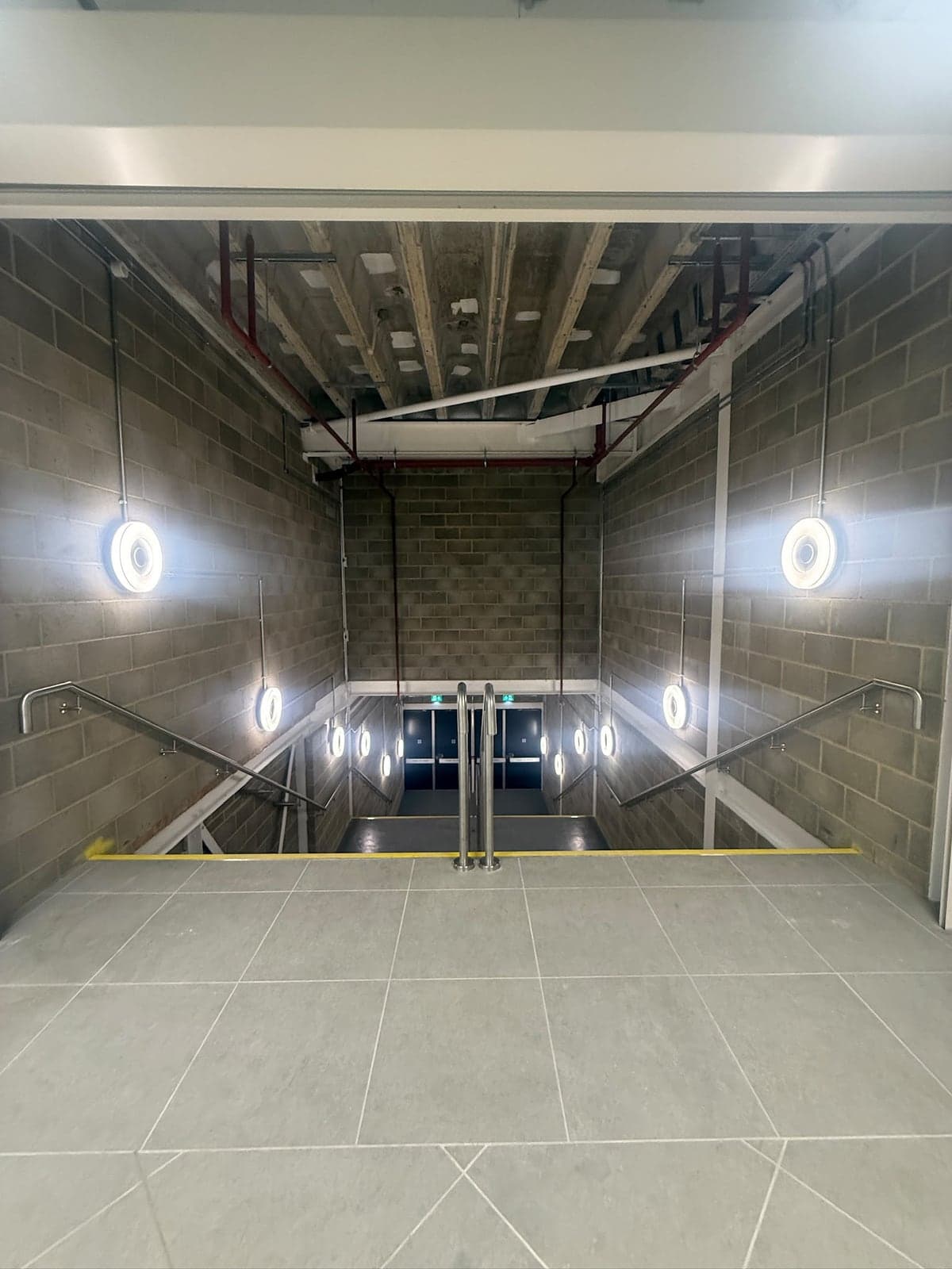 Ring wall lights and steel conduit lighting a new block stairwell